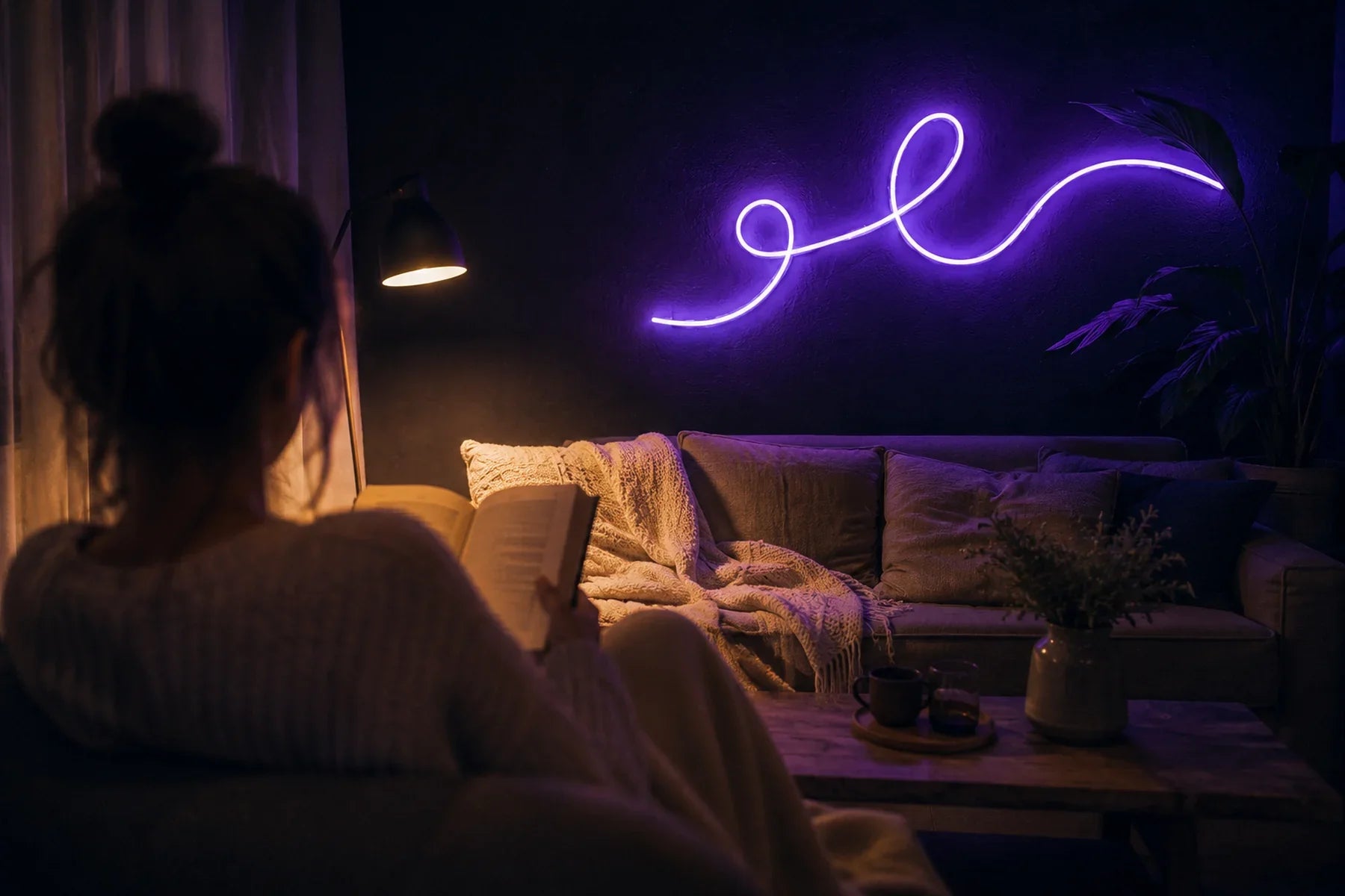 Néon LED violet en écriture cursive au-dessus d'un canapé de salon, personne de dos en train de lire